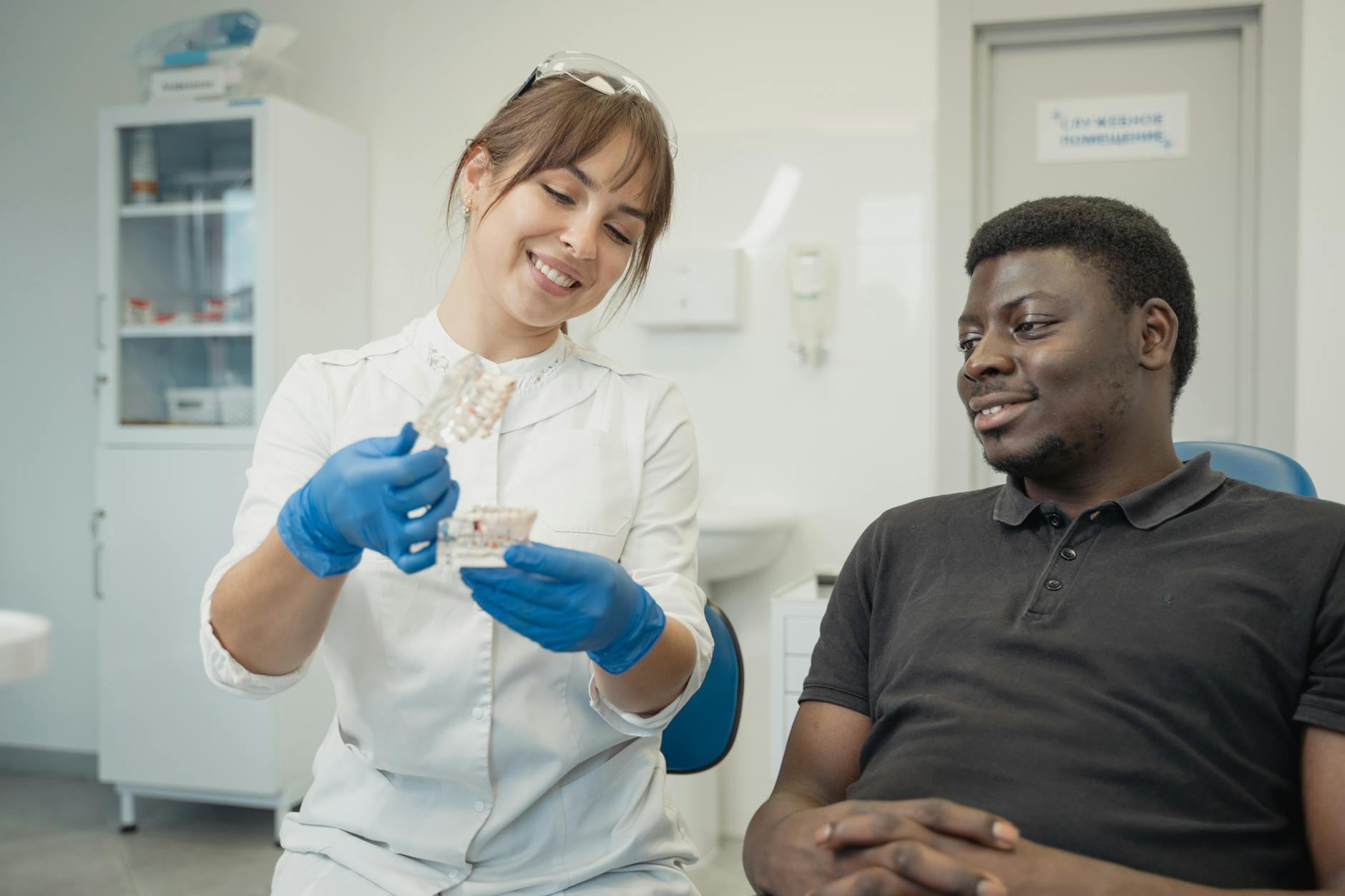 Smiling dentist shows dental model to relaxed patient during consultation